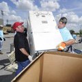 Kenny Reed, left, and John Wiles lift a large copy machine into a cardboard box Thursday at Arvest B...