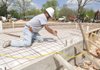 Renny Reyes with Professional Concrete Specialties bends a piece of iron Wednesday while preparing to pour concrete at Ernest Lawrence Plaza, a permanent ice skating rink and splash park, in downtown Bentonville. A change order approved by Bentonville City Council this week will allow for street and sidewalk improvement around Ernest Lawrence Plaza to be done.