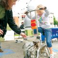 Tammy Todd, an employee at PB2 Architecture and Engineering in Rogers, helps Abby Sullivan, 6, pedal...