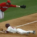 Georgia third baseman Colby May jumps for the ball as Arkansas' Collin Kuhn steals third in the four...