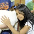 FURRY FARM FRIENDS  - Risay Robert, 8, feels the soft fur of a young boar goat Thursday at the Washi...