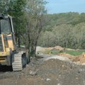 Rick Porterfield from the McDonald County, Mo., Road Department spreads base rock Friday as part of ...