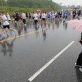 SODDEN STREETS - Karli Jackson, 6, of Rogers watches Saturday as runners participate in the annual S...