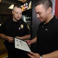 Carlos Castillo, right, admires an award he was presented Tuesday by Highfill Police Chief Jack Sand...
