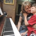 Tayden Larsen, 10, gives mother Casey Larsen a hug Friday while practicing the piano at the family’s...