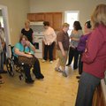 Susan Johnson, seated in a wheelchair, wipes tears from her eyes, surrounded by friends and voluntee...