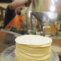 A stack of finished tortillas sits on the scale as owner Jaime Sanchez loads corn flour dough into a...