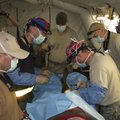Maj. Shea Brannan, wearing the Razorback scarf, operates on a leg in Haiti following the January ear...