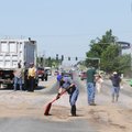 Workers scramble to clean up spilled chicken innards Tuesday on Elm Springs Road in Springdale. A Tr...