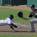  Fayetteville’s Brad Hollenbeck dives back to first base ahead of the pickoff throw to Bentonville’s...