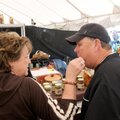  Bentonville High School football coach Rick Rachel gets a bite of a pickled treat Saturday from wif...