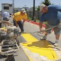 Duston Daniels, right, and Donny Wall, both with Marking Systems of Springdale, paint traffic arrows...