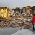 Ann Powell calls her insurance company on Monday while standing in front of what is left of her hous...