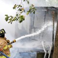 Firefighters hose down the remains of a house destroyed by fire about 11 a.m. Monday on Colonel Meye...