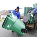 Anthony Rodriguez, left, with Rehrig Pacific Company, carries a new Waste Management cart to a Sprin...