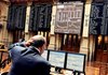 A trader watches computer screens displaying stock movements Friday on the exchange in Madrid, Spain.