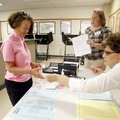Linda Bruce, left, of Bella Vista checks in with election officials Kim Stevens of Rogers and Nancy ...