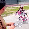 Raymond Gomez watches as his helmeted and padded daughter Angelina Gomez, 7, tries braking and dismo...