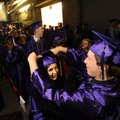 Fayetteville High School senior Dylan Holland, right, helps Huntley Hudgins with her mortar board Th...