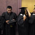 Jessica Turcios, right, helps Astrid Martinez with her mortarboard Friday with other graduates of th...