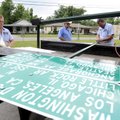 Eric Carter, right, signs and marking technician, trims a pole Tuesday as Troy Lewis, left, signs an...