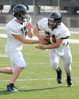 Bentonville running back Alberto Hernandez takes the handoff from quarterback Pearson Gean during spring practice Monday in Tiger Stadium in Bentonville.