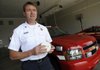 Micheal Dean, Rogers Fire Department public information officer, talks Wednesday about the dual sensor smoke detectors the department is distributing as part of a new program to saturate neighborhoods affected by a recent residential fire.