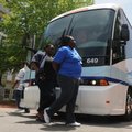 Walmart associates step off a bus Thursday at the Bentonville square while touring attractions befor...