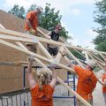 Habitat for Humanity volunteers lift a roof truss Friday at a new house in Centerton. The house is t...