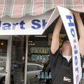 Tyler Hobson takes down a Walmart shareholders meeting banner Monday in front of the Station Cafe in...
