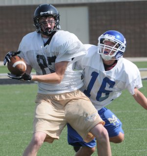 Bentonville’s Luke Crenshaw catches a pass Thursday while being covered by Mountain Home’s Hunter Thorpe at Tiger Stadium in Bentonville. Bentonville hosted Mountain Home, Shiloh Christian and Jenks, Okla., for a football camp.
