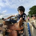 Meranda Wilkerson helps Elijah Patterson into the saddle Thursday before taking a ride on Buttercup,...