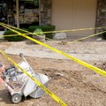 Ed Rush of Rush Concrete resets caution tape Monday before a back hoe moves in to scoop out pulveriz...