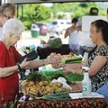 Issabelle Ernst, left, buys vegetables Tuesday from Mamg Moua at the Springdale Farmers Market at th...