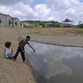 A pair of youngsters play Wednesday on the bank of a pond at Doc Mashburn Park. Fayetteville Parks a...