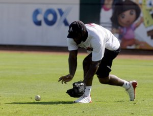 Arkansas wide receiver Carlton Salters scoops up a ground ball hit to right field during drills at the Kansas City Royals tryout June 18 in Arvest Ballpark in Springdale.