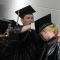 Ron Lee helps Karen Lankford with her tassel Tuesday as they wait in line for the start of Northwest...