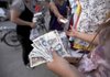 A Chinese woman who sells clothing on the roadside in Beijing carries a handful of yuan on Tuesday. 