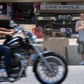 Reece Taylor, 11, holds a sign Wednesday at his lemonade and cold coffee stand to a passing motorcyc...