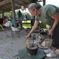 DUTCH OVEN DEMO - Tammy Evans brushes ash off the top of a Dutch oven pot as she teaches a class on ...
