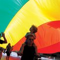 Ben Buonaiuto and his son Ari Buonaiuto, 4, walk under a large flag down Dickson Street during the P...