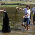Landon Walker, left, with First Baptist Church in Rogers, holds a trash bag open for Emily Walker, 1...