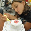 Magan Pine of Hindsville works Thursday on decorating her cake during a cake decorating class put on...