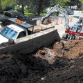 Workers with the Johnson Street Department move dirt on Sunday from a retaining wall on Main Drive t...