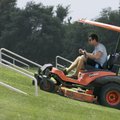 Richard Waggoner takes his mower up a small hill beside Tyson Middle School in Springdale on Monday....