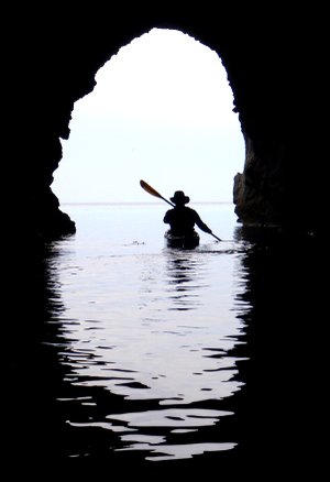 Kayak guide Rod Feldtmann paddles back into the light after exploring a cave on the north coast of Milos, Greece, on April 24. The sea caves that dot most of the coast of Milos help make the island a world class warm water paddling destination.