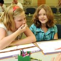 Meredith Laman, 8, left, and Savannah Peters, 8, laugh as they create their dream playground Tuesday...