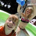 Caitlin Moore, 11, right, dumps water on her neighbor Kyleigh Holliday, 2, while playing Wednesday i...
