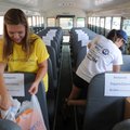 STUFF THAT BUS - Ashton Barnett, left, a volunteer with Ernst & Young of Rogers, and Meredith Bergst...
