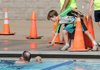 After competing in his own age division, Daniel Hines, 10, hands his father, Joe Hines, his glasses Saturday at the end of his swim in the Kids and Family Shark Fest IV Triathlon at Memorial Park in Bentonville. Daniel’s mother, Lainie Hines, and brother, Will Hines, also competed in the triathlon.